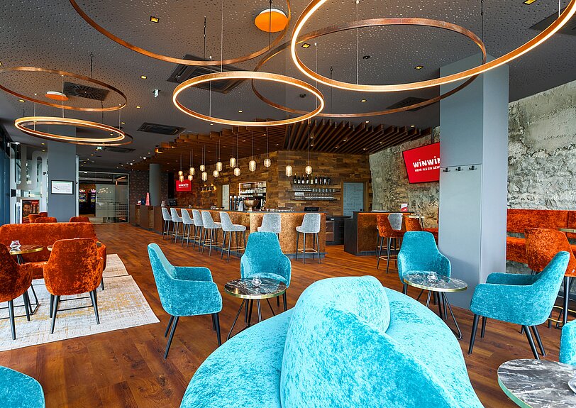 Gastronomiebereich im WINWIN Hallein mit Blick auf edle Lounge-Moebel in blau und orange.