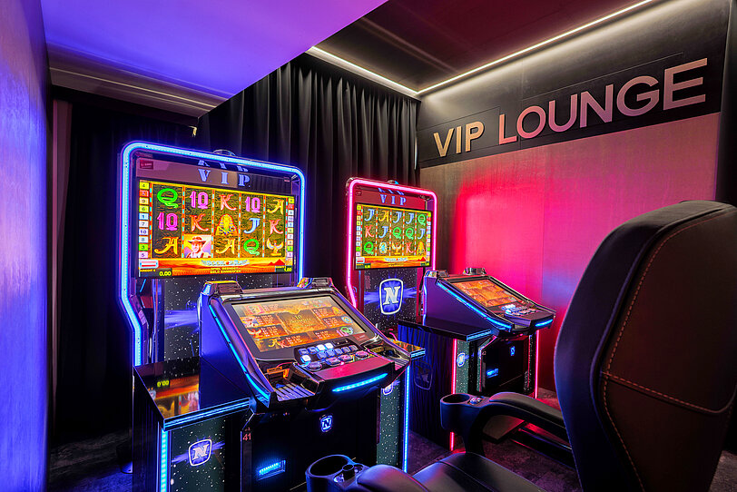 Zwei elegant beleuchtete VIP-Video Lottery Terminals im WINWIN Krems mit aktivem Spiel Book of Ra Deluxe.