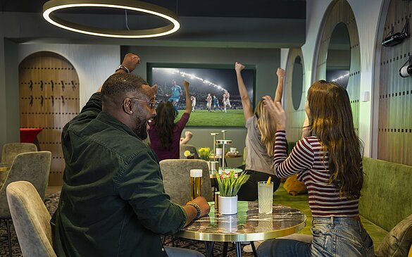 WINWIN Gäste jubeln während im Fernsehen Fußball läuft
