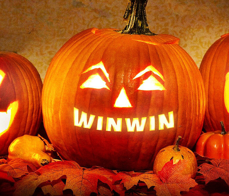 Drei leuchtende Halloween-Kürbisse vor dunklem Hintergrund.