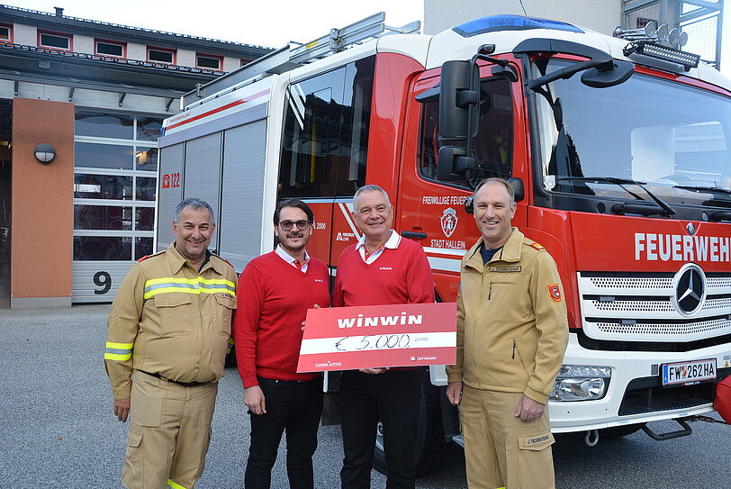 WINWIN Hallein Team ueberreicht Freiwillige Feuerwehr Hallein einen Spendenscheck.
