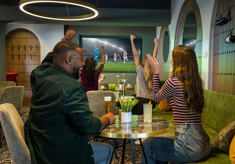 Einige Gäste schauen im WINWIN zusammen ein Fußballspiel und jubeln 