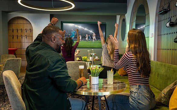 Einige Gäste schauen im WINWIN zusammen ein Fußballspiel und jubeln 