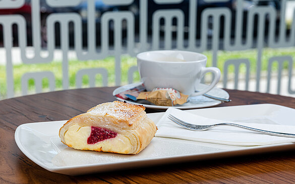 Topfen-Himbeer Strudel mit Staubzucker und Tasse Kaffee im Gastgarten von WINWIN.