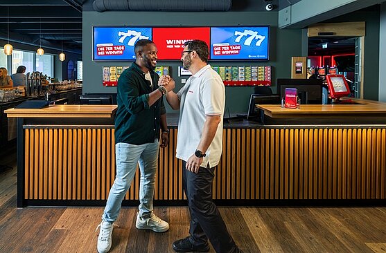 Ein Mitarbeiter von WINWIN und ein Gast begrüßen sich mit Handschlag.