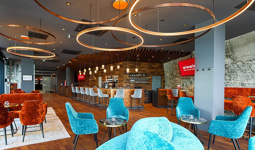 Gastronomiebereich im WINWIN Hallein mit Blick auf edle Lounge-Moebel in blau und orange.