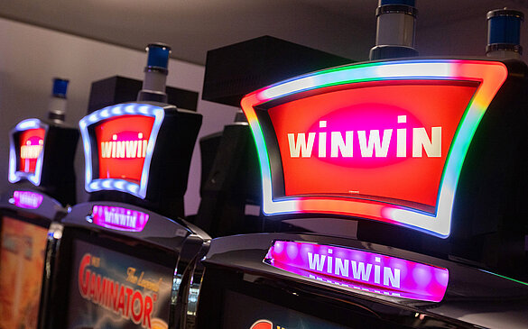 Leuchtendes WINWIN-Logo am Novomatic Upright VLT im Spielbereich von WINWIN Landeck.