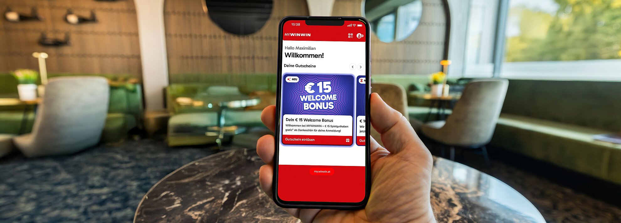 Ein Mobiltelefon wird von einer Hand gehalten und zeigt den Welcome Bonus für MYWINWIN