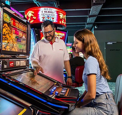 WINWIN Mitarbeiter erklärt weiblichem Gast den Video Lottery Terminal