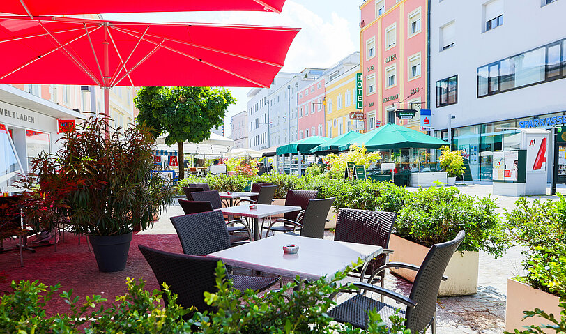 Der gemuetliche Gastgarten von WINWIN Voecklabruck mit zahlreichen gruenen Pflanzen.