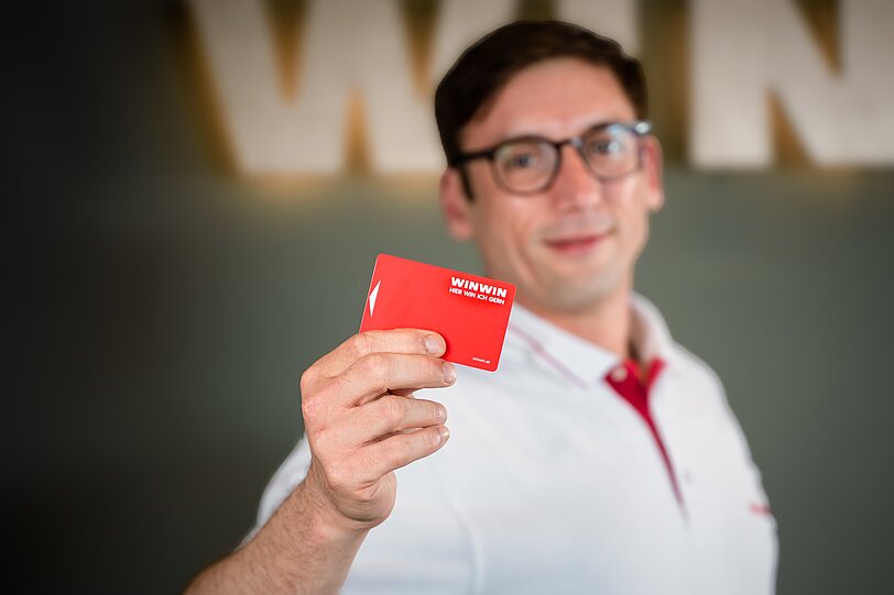 Ein WINWIN Mitarbeiter hält die WINWIN Karte in die Kamera