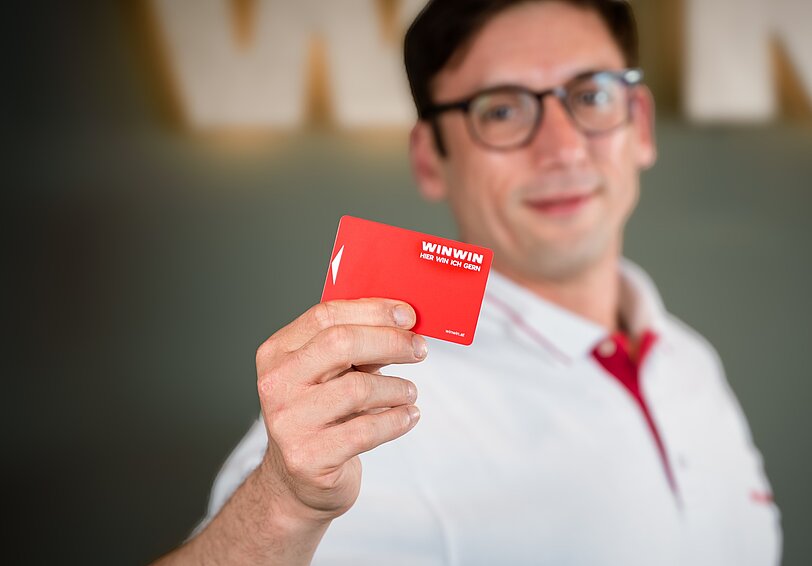 Ein WINWIN Mitarbeiter hält die WINWIN Karte in die Kamera