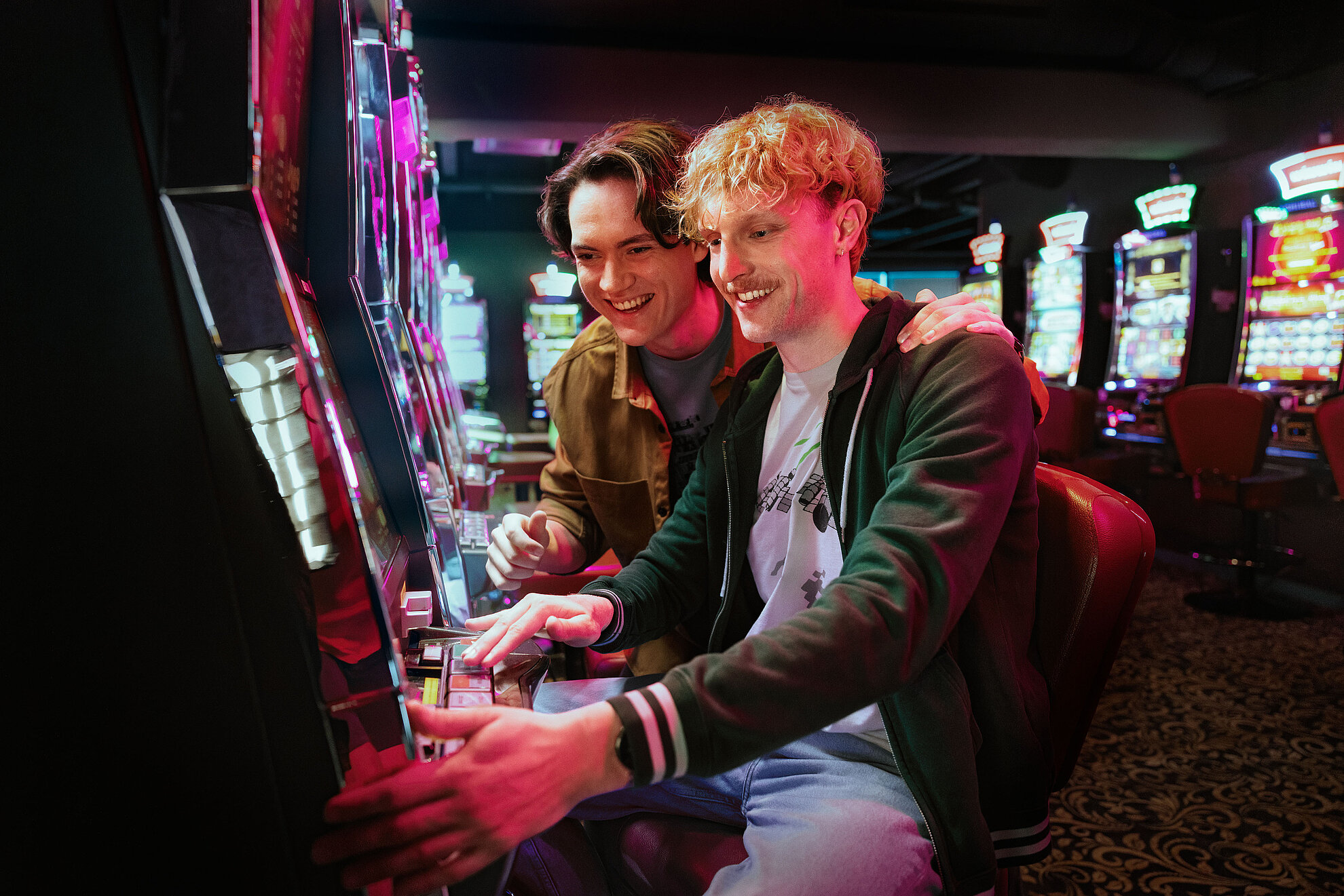 Zwei junge Männer, die an einem Automat spielen.
