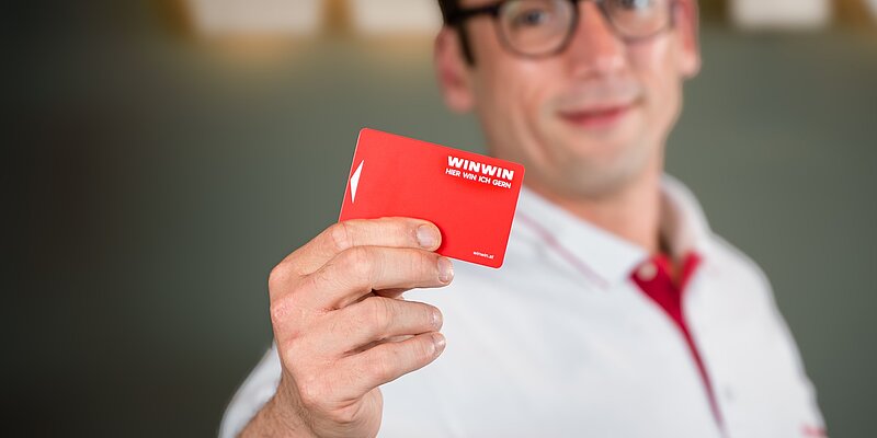 Mitarbeiter hält WINWIN Karte in die Kamera