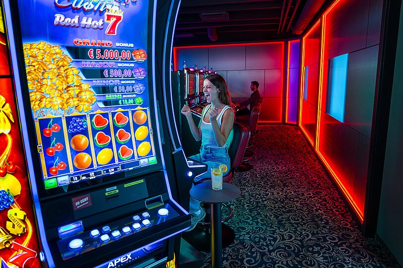 Eine Frau sitzt an einem Spielautomat und jubelt