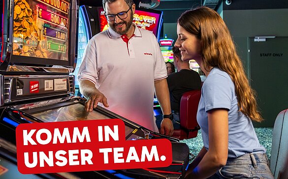 Der Text "Komm in unser Team." befindet sich auf dem Bild eines WINWIN Mitarbeiters, der einem Gast den Spielautomat erklärt