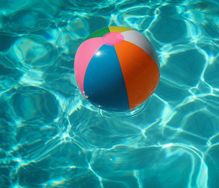 Bunter Wasserball schwimmt auf der Wasseroberfläche eines Pools.