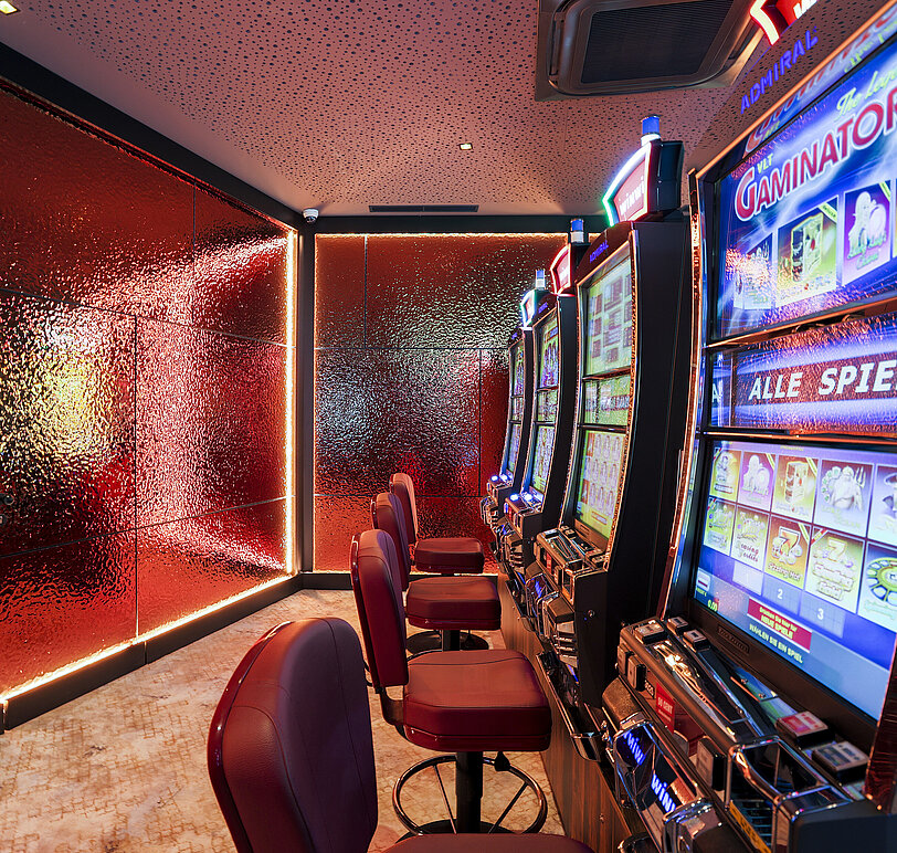 Novomatic-VLTs und rotes, beleuchtetes Wanddesign im Spielbereich von WINWIN Hallein.