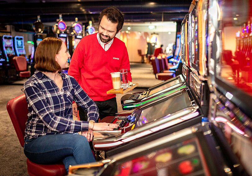 WINWIN Mitarbeiter serviert Barista-Kaffee an Kundin im Spielbereich.