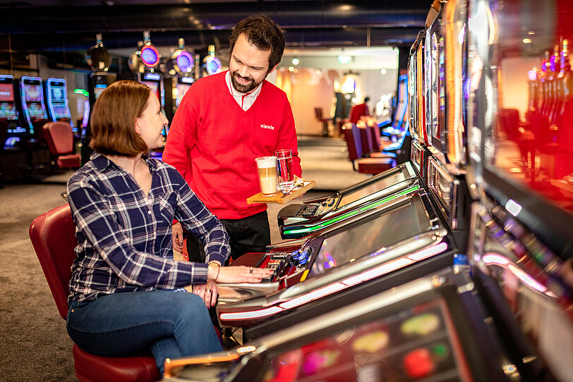 WINWIN Mitarbeiter serviert Barista-Kaffee an Kundin im Spielbereich.