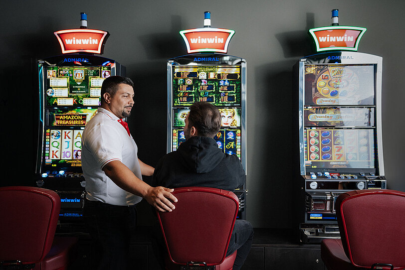 Ein WINWIN Mitarbeiter betreut einen Gast am Spielautomat