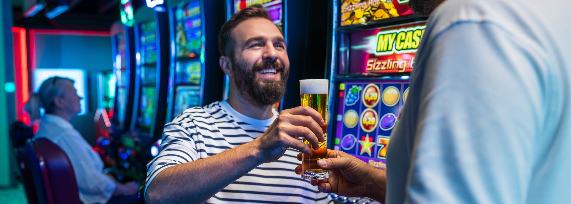 Ein Mann erhält von einem WINWIN Mitarbeiter ein Getränk an den Spielautomat 